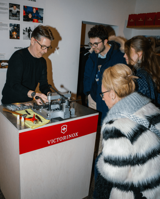 5 A Victorinox representative demonstrates a multi-tool assembly process to an engaged audience at a promotional event, showcasing the brand's craftsmanship and innovation.
