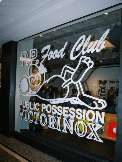 6 Window display of the P.P. Food Club featuring a playful illustration and branding for Public Possession and Victorinox, highlighting a vibrant and creative atmosphere.