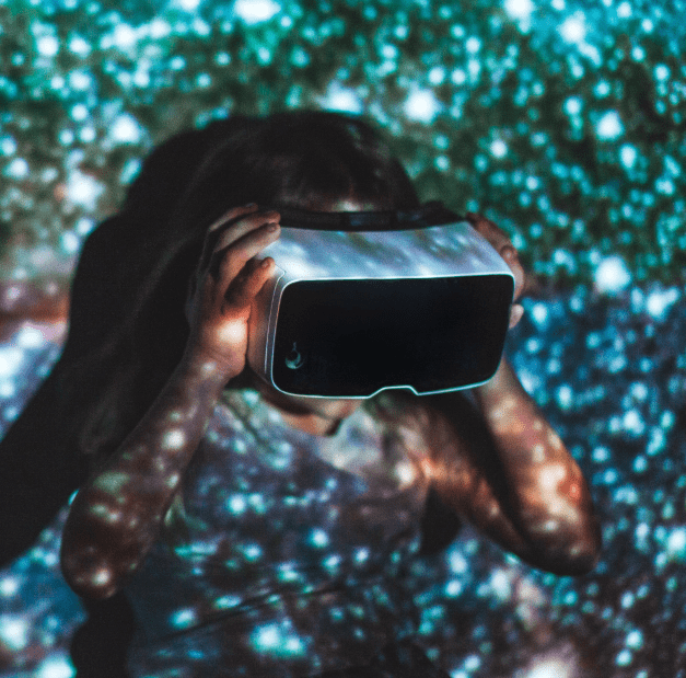 Child wearing a virtual reality headset, surrounded by colorful starry projections on the wall, exploring immersive technology and digital experiences.